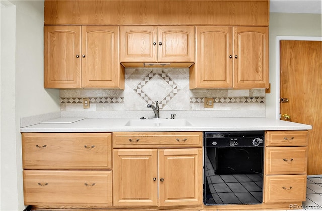 kitchen with dishwasher, light brown cabinets, and a sink