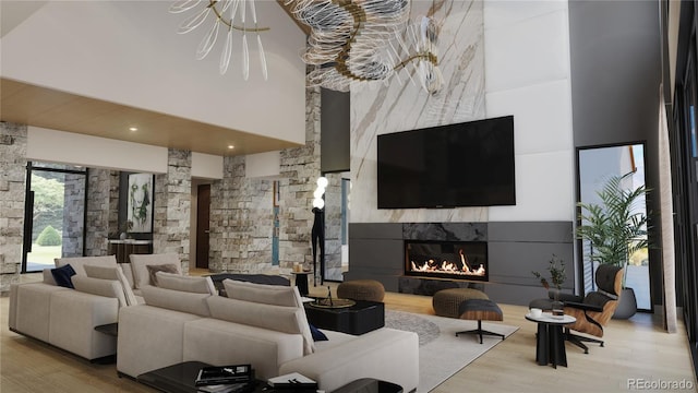 living room featuring a large fireplace, light hardwood / wood-style floors, a towering ceiling, and an inviting chandelier