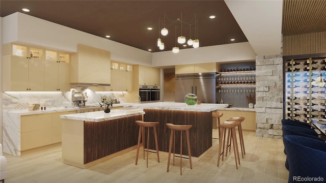 kitchen with backsplash, a breakfast bar, stainless steel appliances, light hardwood / wood-style floors, and a large island