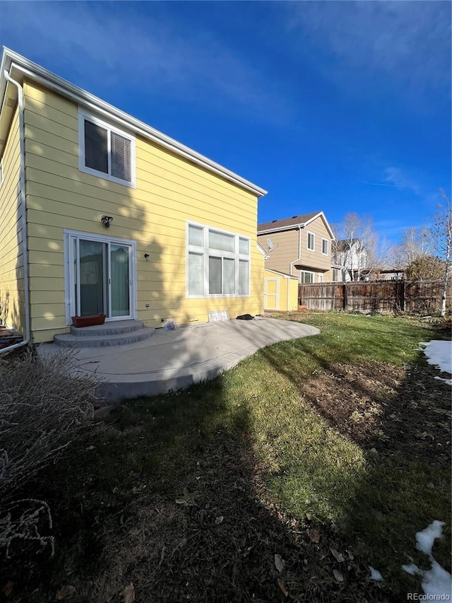 back of property with a lawn and a patio area