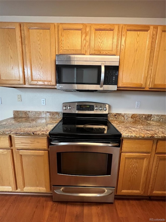 kitchen with dark wood-type flooring, stone countertops, and appliances with stainless steel finishes