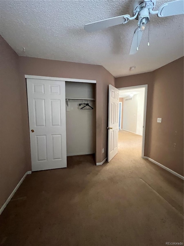 unfurnished bedroom with ceiling fan, a closet, carpet floors, and a textured ceiling