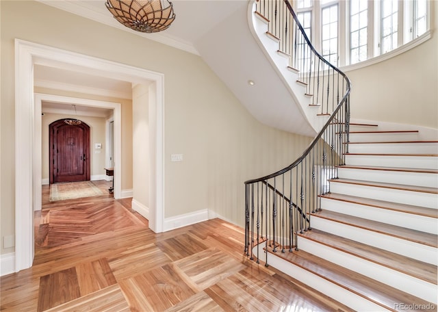 staircase featuring crown molding and parquet flooring