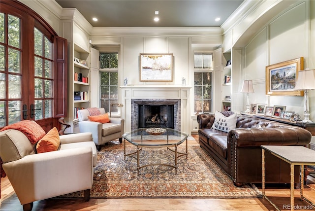 living room featuring crown molding, built in shelves, wood-type flooring, and french doors