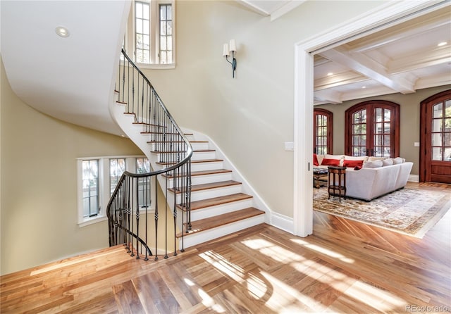 staircase with beam ceiling, plenty of natural light, french doors, and wood-type flooring