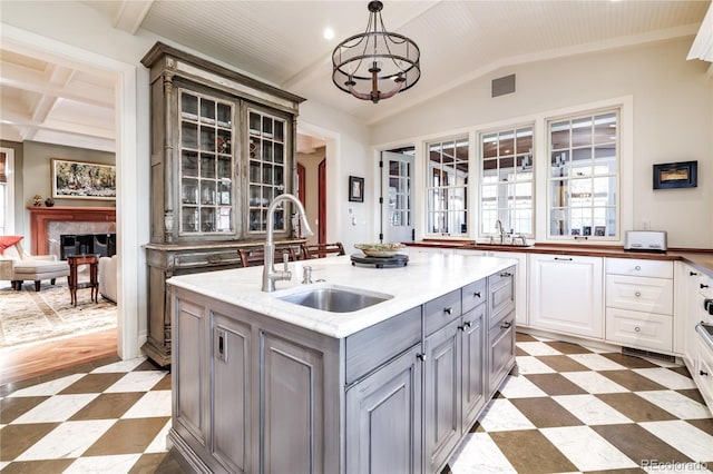 kitchen featuring sink, gray cabinetry, white cabinetry, pendant lighting, and a kitchen island with sink