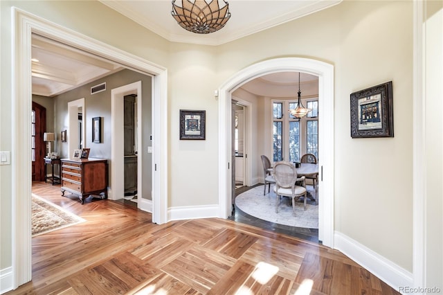 corridor with parquet floors, ornamental molding, and a chandelier