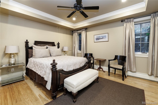 bedroom featuring a raised ceiling, crown molding, ceiling fan, and light hardwood / wood-style flooring