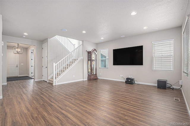 unfurnished living room featuring a textured ceiling, stairs, recessed lighting, baseboards, and wood finished floors