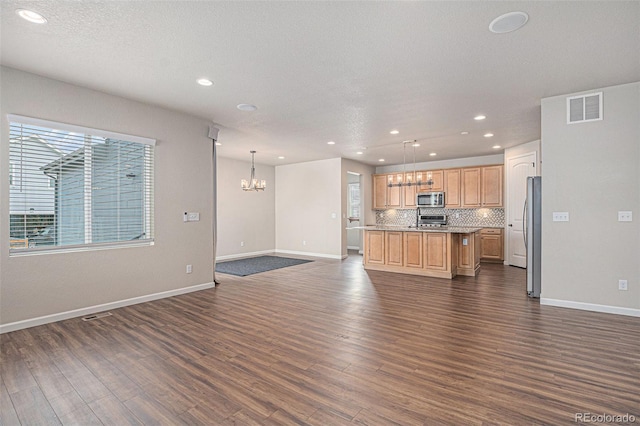 unfurnished living room with an inviting chandelier, baseboards, recessed lighting, and visible vents