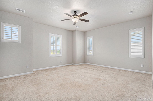 spare room featuring visible vents, a textured ceiling, ceiling fan, and a healthy amount of sunlight