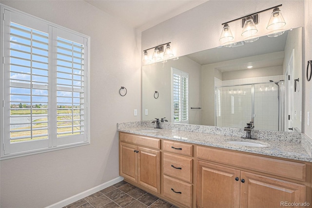 bathroom with a sink, baseboards, a stall shower, and double vanity