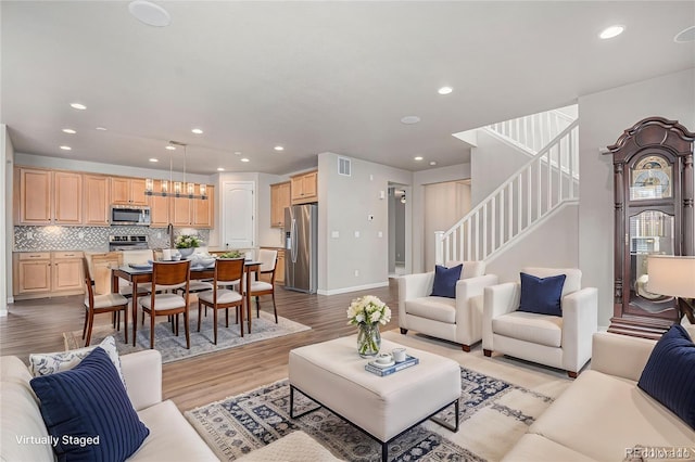 living area with stairs, recessed lighting, visible vents, and light wood-style flooring