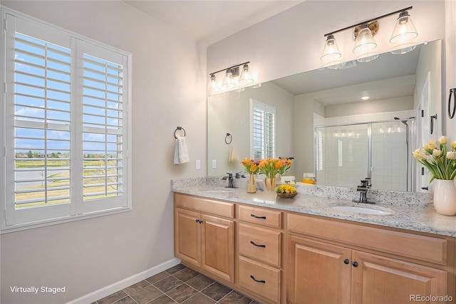 full bathroom with double vanity, baseboards, a shower stall, and a sink