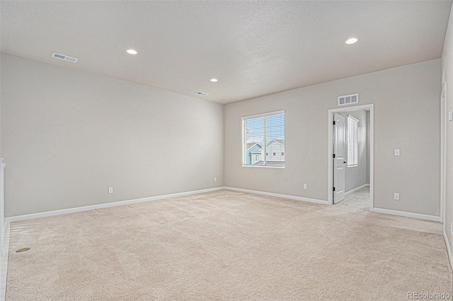 spare room with light colored carpet, visible vents, and recessed lighting
