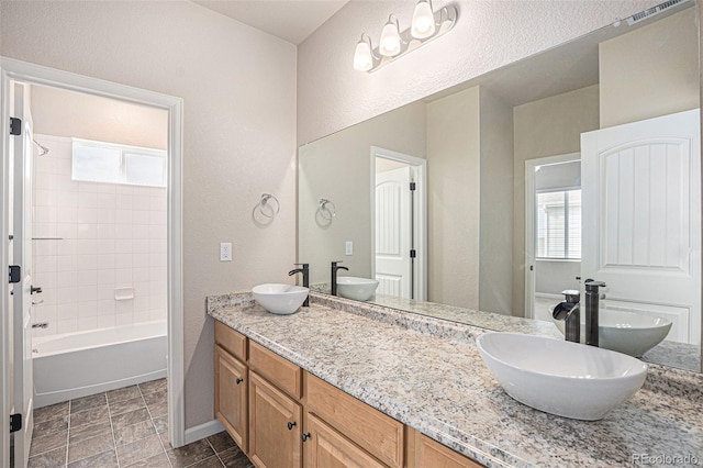 bathroom with visible vents, a sink, a textured wall, and double vanity