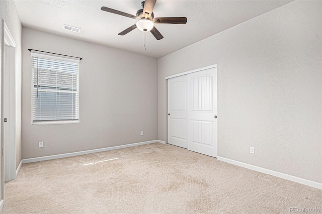 unfurnished bedroom with baseboards, light carpet, a closet, and visible vents