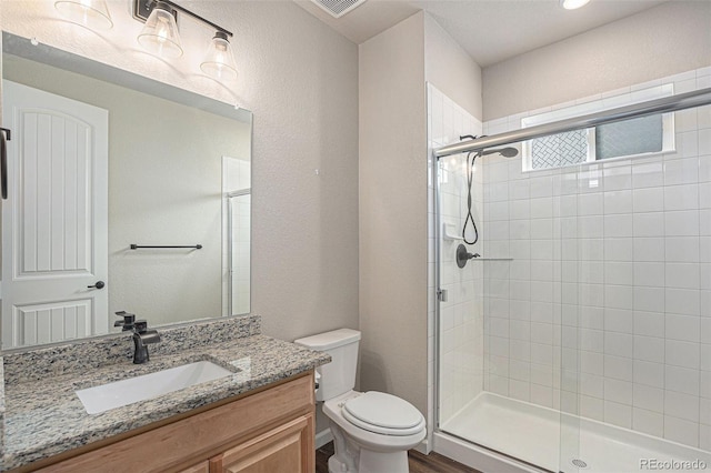 bathroom featuring vanity, toilet, wood finished floors, and a stall shower