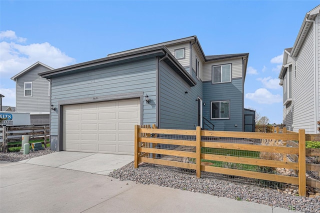 view of side of property featuring an attached garage, concrete driveway, and fence private yard