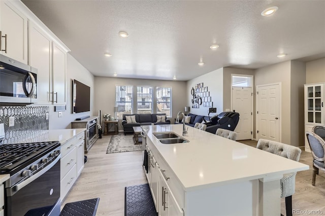 745 N Tempe St, Aurora, CO 80018 - kitchen with appliances with stainless steel finishes, a center island with sink, a sink, light countertops, and open floor plan