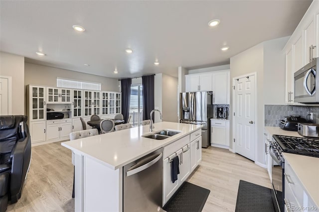 745 N Tempe St, Aurora, CO 80018 - kitchen featuring appliances with stainless steel finishes, tasteful backsplash, a sink, light countertops, and light wood finished floors
