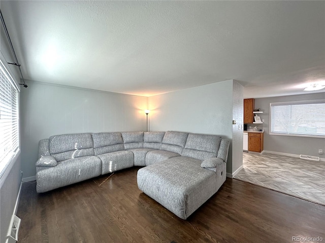 living room featuring baseboards, visible vents, and wood finished floors