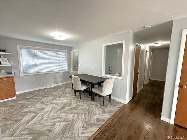 dining room featuring visible vents, baseboards, and wood finished floors