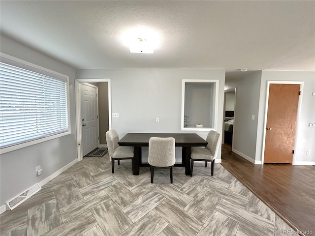 dining space with a textured ceiling, visible vents, and baseboards