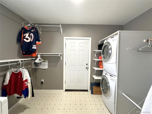 clothes washing area featuring stacked washer / dryer, laundry area, baseboards, and light floors