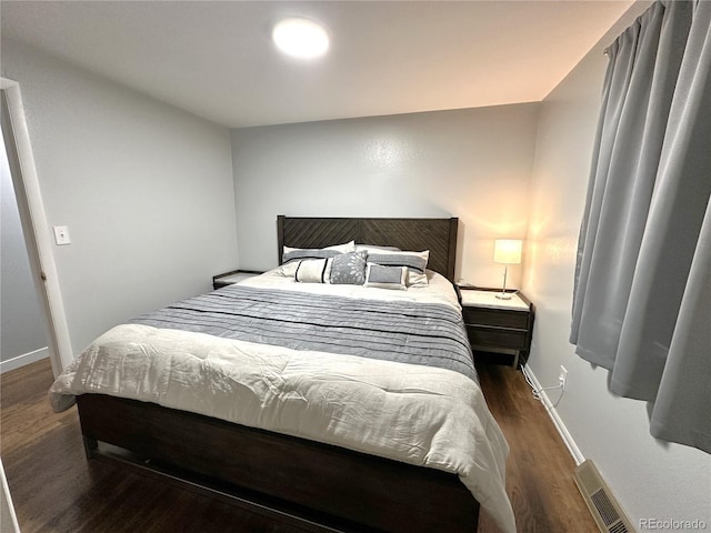 bedroom with baseboards, visible vents, and wood finished floors