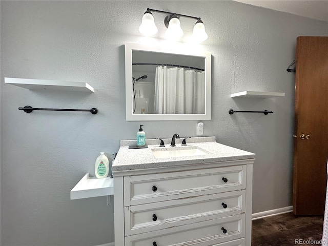 full bathroom with a shower with curtain, a textured wall, and vanity