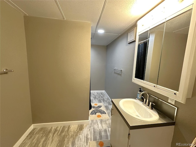 bathroom featuring curtained shower, vanity, baseboards, and wood finished floors