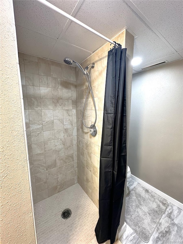 full bathroom featuring toilet, visible vents, baseboards, and tiled shower