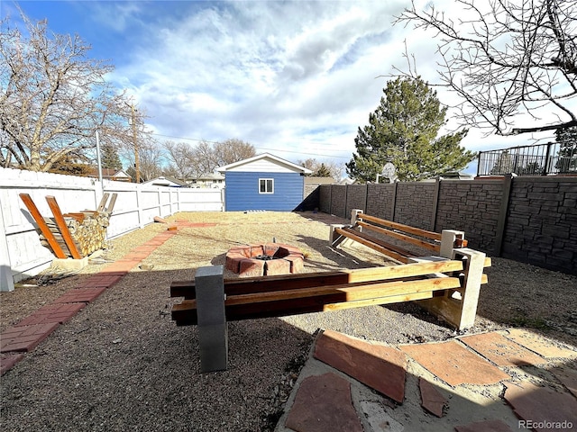 view of yard featuring a fire pit, an outdoor structure, and a fenced backyard