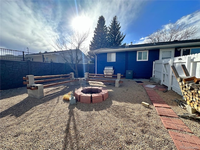 back of house with an outdoor fire pit and a fenced backyard