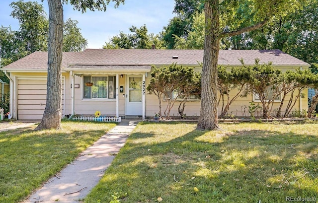 single story home featuring a garage, a shingled roof, and a front lawn