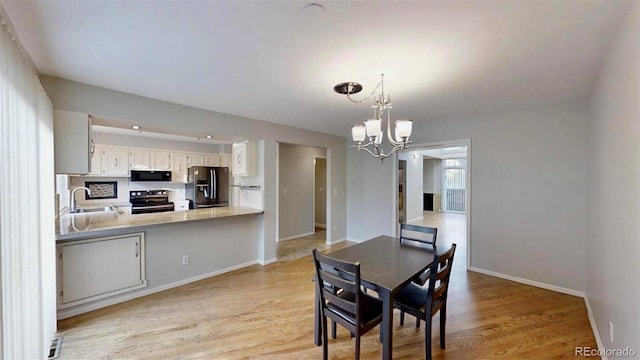 dining space with sink, an inviting chandelier, and light wood-type flooring