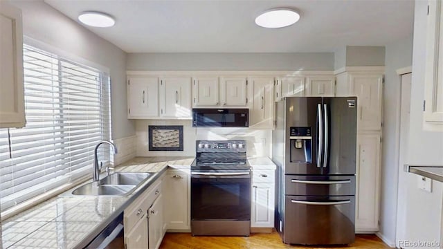 kitchen featuring sink, white cabinetry, light wood-type flooring, stainless steel appliances, and backsplash