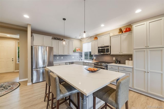 19688 E 52nd Ave, Denver, CO 80249 - kitchen with appliances with stainless steel finishes, a sink, light wood-style floors, a kitchen island, and recessed lighting