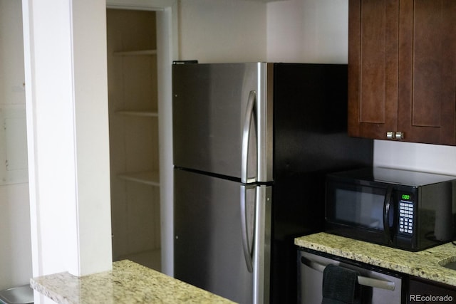 kitchen featuring light stone countertops, appliances with stainless steel finishes, and dark brown cabinetry