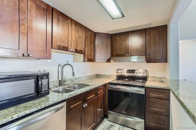 kitchen featuring light stone countertops, appliances with stainless steel finishes, sink, and a textured ceiling