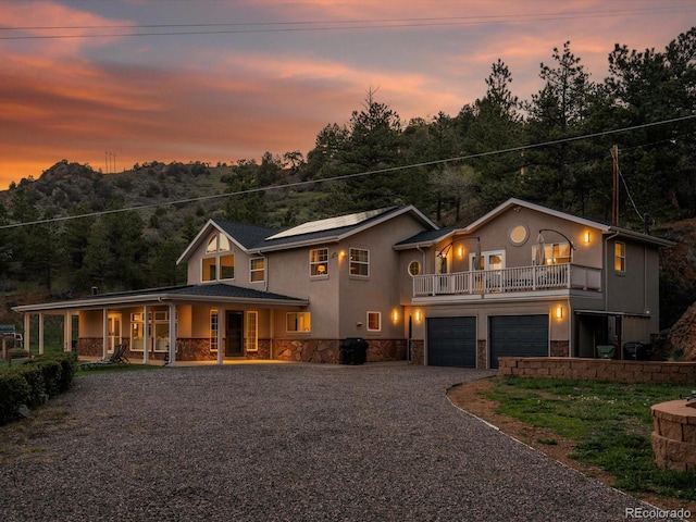 2571 SW Grapevine Rd, Idledale, CO 80453 - view of front of home with stone siding, a porch, stucco siding, driveway, and a garage