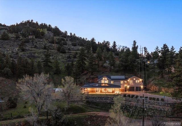 2571 SW Grapevine Rd, Idledale, CO 80453 - rear view of house featuring solar panels and a wooded view