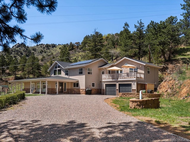 2571 SW Grapevine Rd, Idledale, CO 80453 - view of front of house with stone siding, driveway, a garage, covered porch, and solar panels