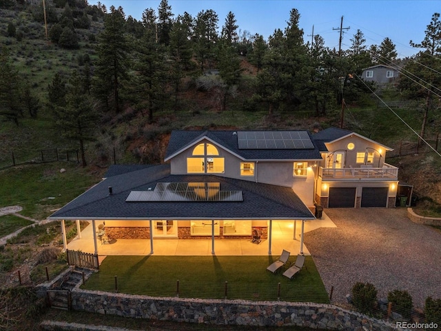 2571 SW Grapevine Rd, Idledale, CO 80453 - rear view of house with stucco siding, solar panels, a garage, gravel driveway, and a patio area