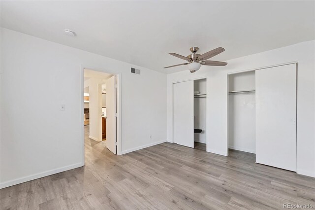 unfurnished bedroom featuring ceiling fan, light hardwood / wood-style floors, and multiple closets