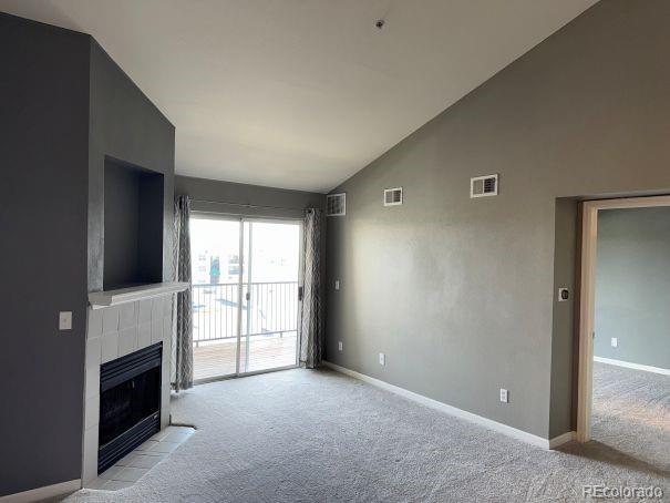12304 W Cross Dr Unit 304, Littleton, CO 80127 - unfurnished living room featuring light colored carpet, a fireplace, and high vaulted ceiling