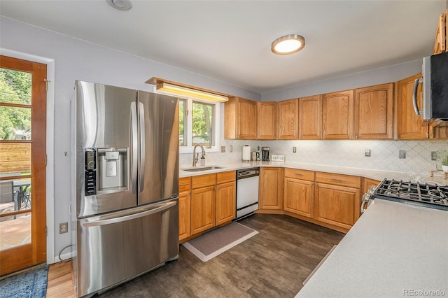 kitchen featuring dark wood-style floors, stainless steel appliances, light countertops, backsplash, and a sink