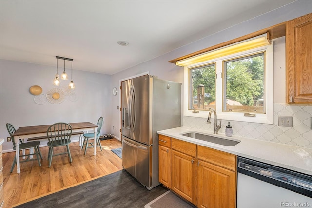 kitchen with tasteful backsplash, stainless steel fridge, dark wood-style flooring, white dishwasher, and a sink