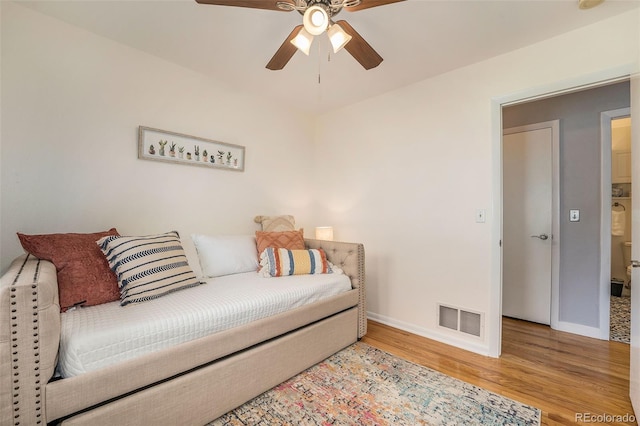 bedroom with baseboards, visible vents, ceiling fan, and wood finished floors